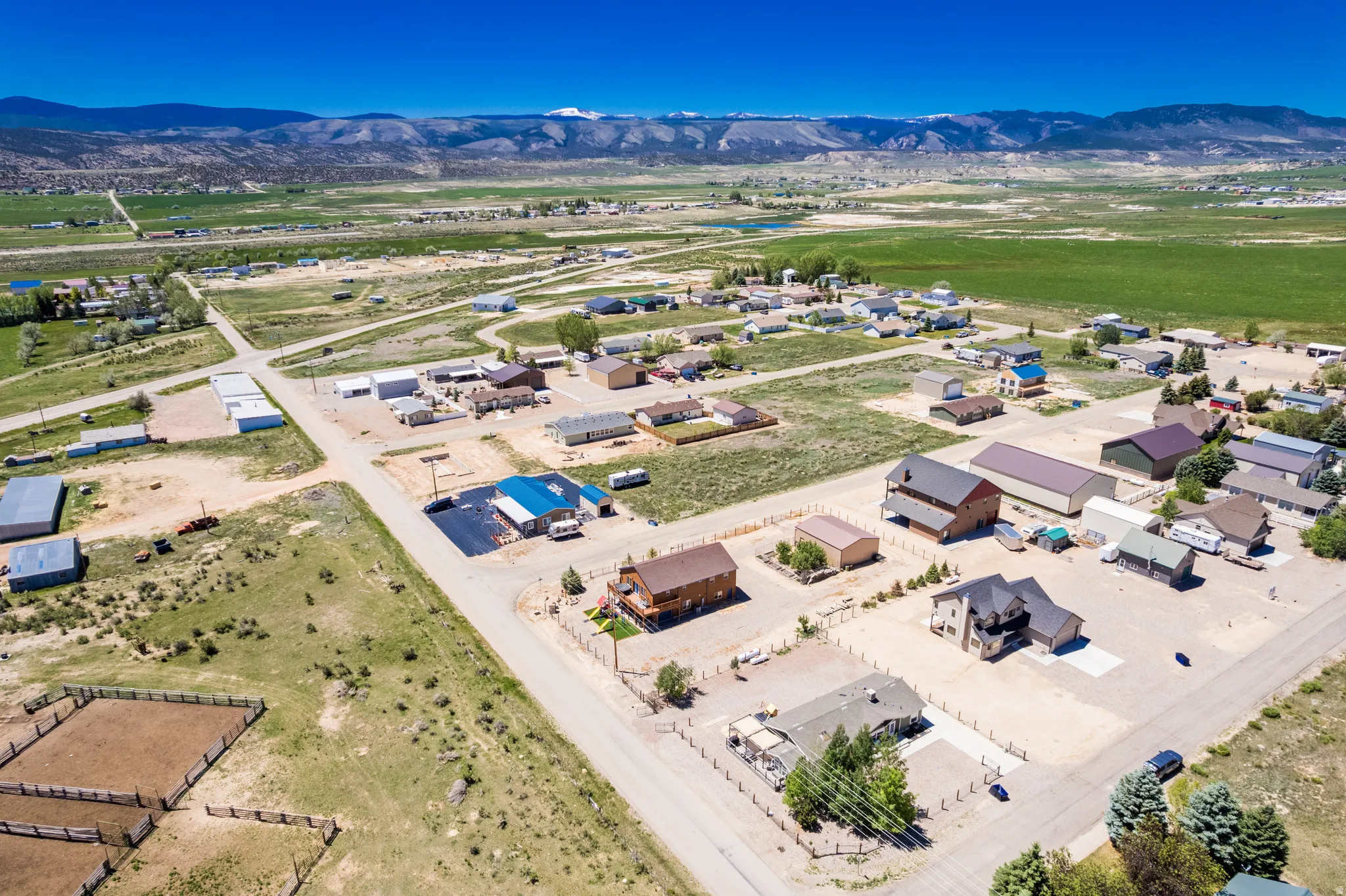 Expansive rural landscape featuring a dispersed settlement of residential and commercial structures, surrounded by undeveloped land and distant mountain ranges