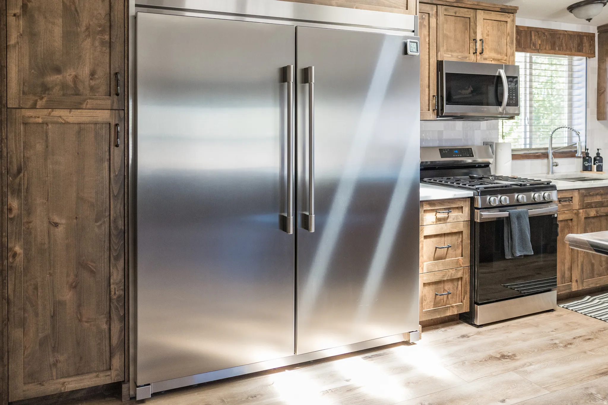 Kitchen featuring a built-in stainless steel side-by-side refrigerator, gas range, and microwave