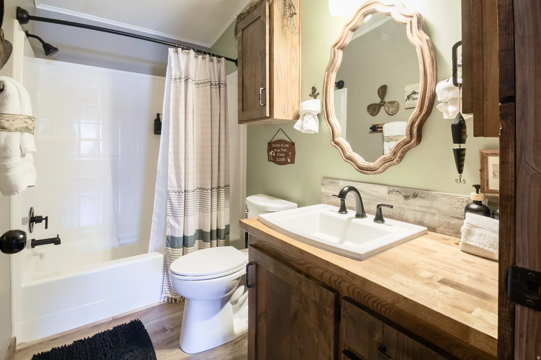 Bathroom featuring a white tub/shower combination with a matte black showerhead and faucet, a vanity with a light wood-finish countertop, a rectangular undermount sink, and a black two-handle faucet
