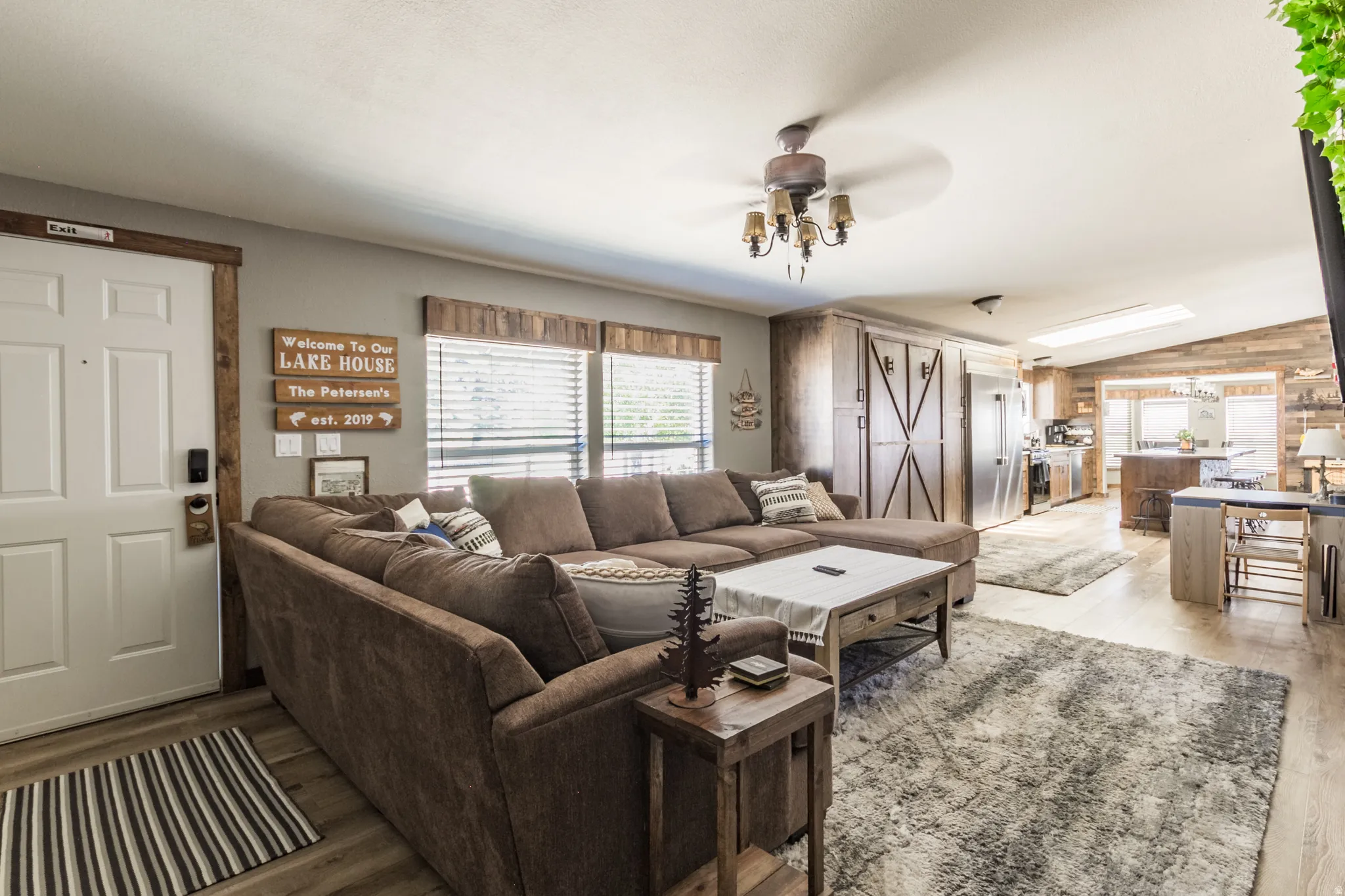 Open concept living area featuring wood-finish flooring, a ceiling-mounted light fixture, and horizontal window blinds