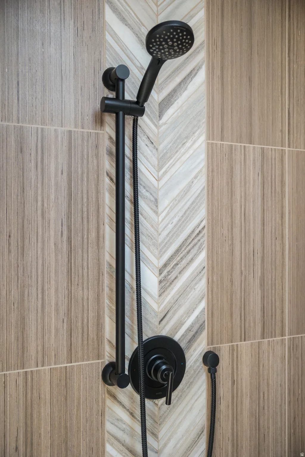 Matte black shower fixture with a handheld sprayer and integrated controls