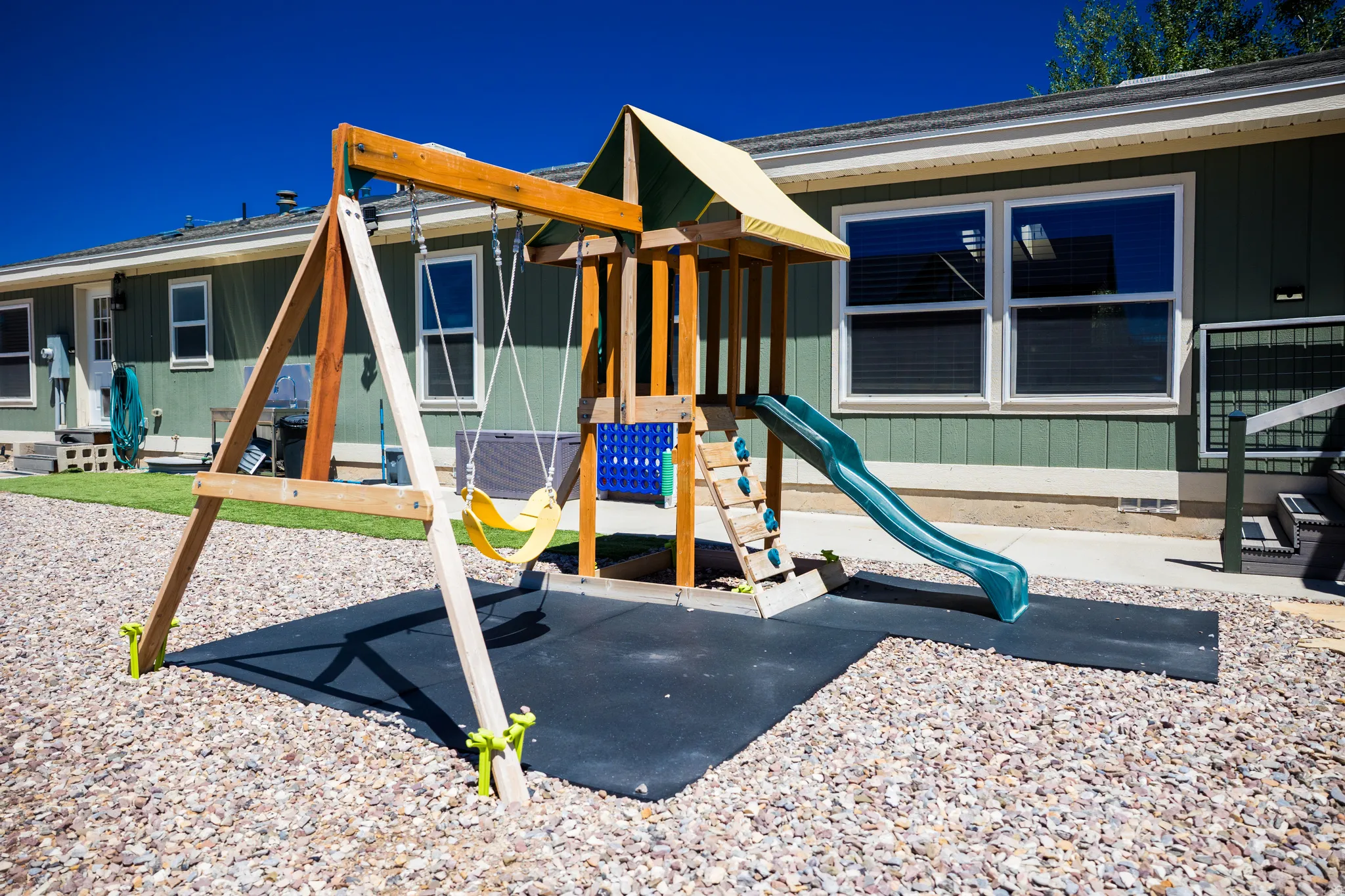 Outdoor play structure featuring a slide, swings, and a climbing ladder