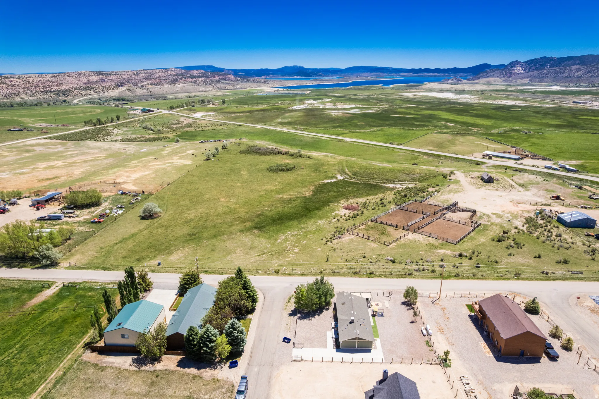 Expansive rural property featuring multiple residential structures, open fields, and distant mountain and water scenery