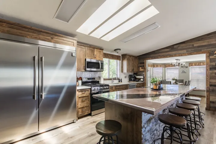 Kitchen featuring a large central island with seating, stainless steel appliances, wood-finish flooring, recessed lighting, and wood cabinetry