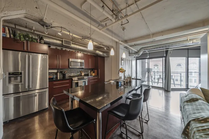 Modern kitchen featuring stainless steel appliances, dark wood cabinetry, and a patterned tile backsplash