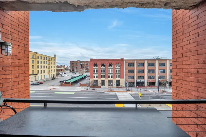 Balcony overlooking an urban streetscape with distinct brick buildings and a covered parking area