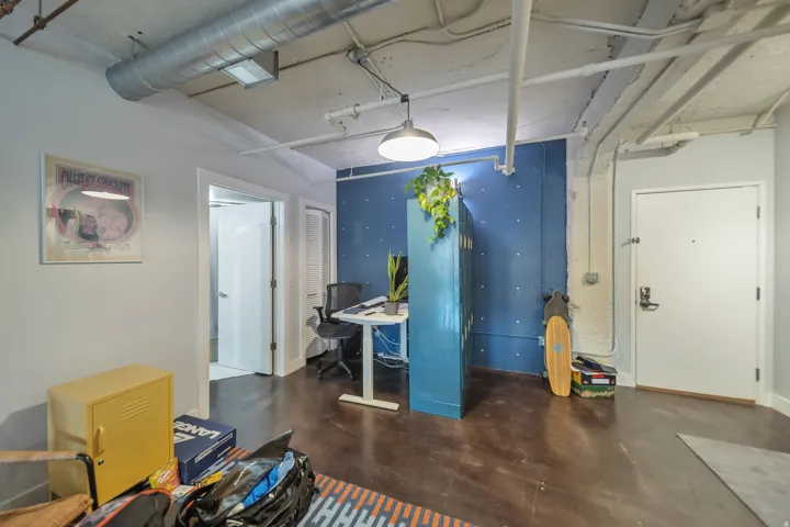 Concrete flooring with a polished finish, exposed ceiling ductwork, and a built-in office area with a blue accent wall