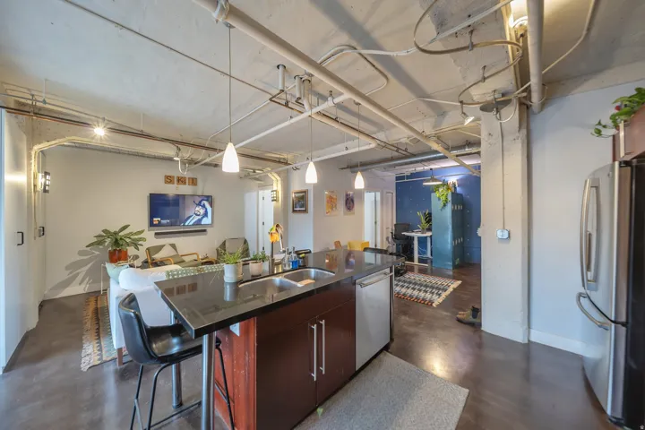Kitchen island with a dark countertop and integrated stainless steel sink, featuring a stainless steel dishwasher