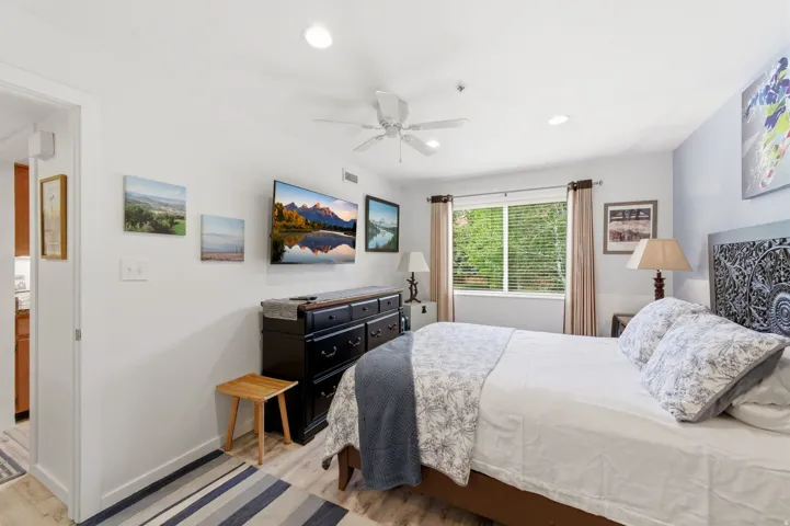 Well-lit room featuring wood-finish flooring and a ceiling fan