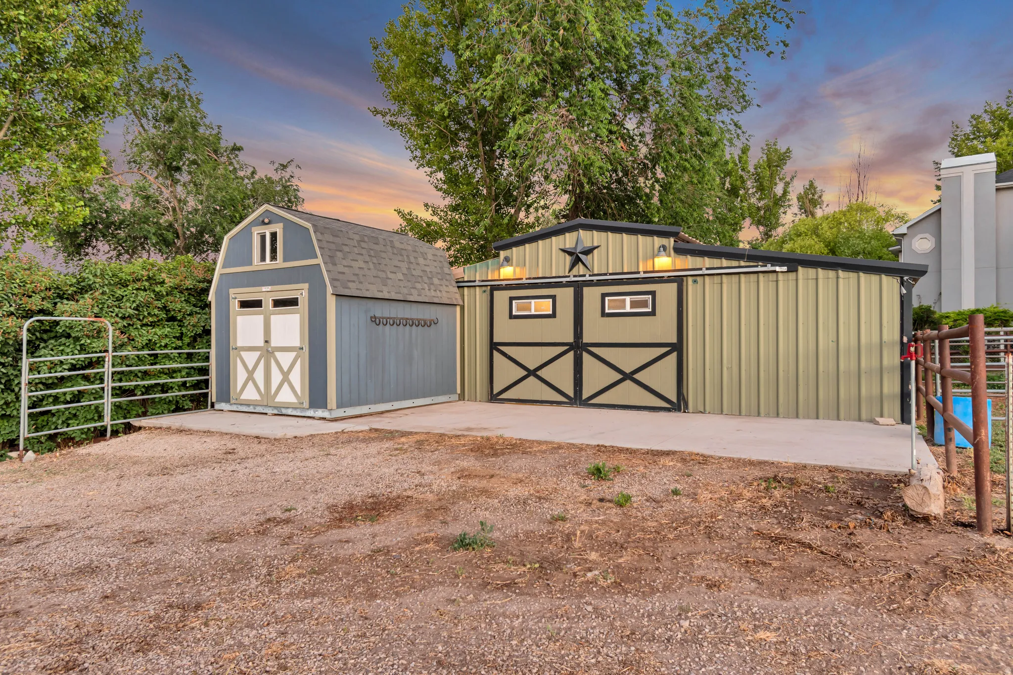Two outbuildings featuring a gambrel-roofed shed with double doors and a larger metal-sided structure with barn-style doors
