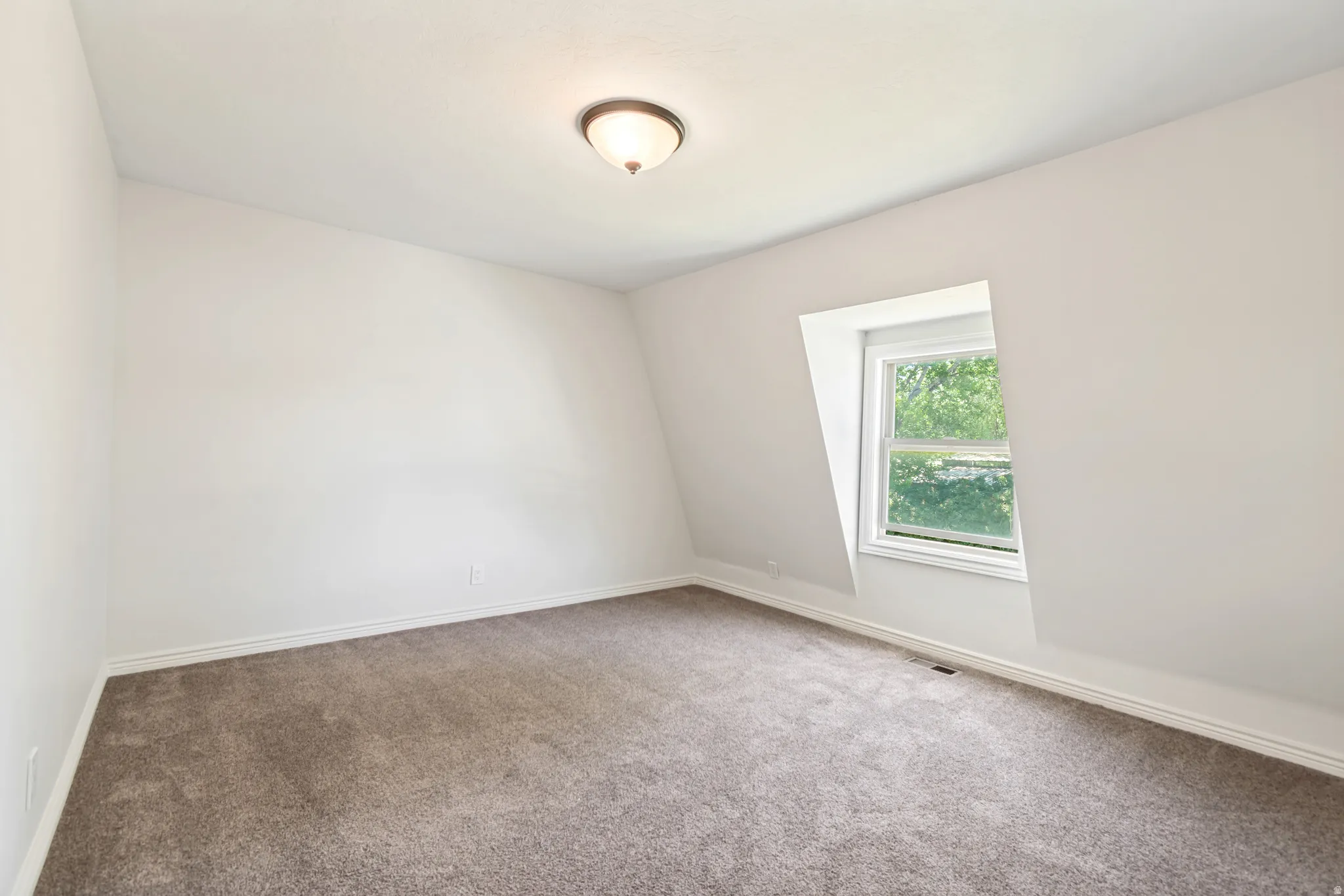 Room featuring a dormer window, gray carpet, white baseboards, and a semi-flush mount ceiling light