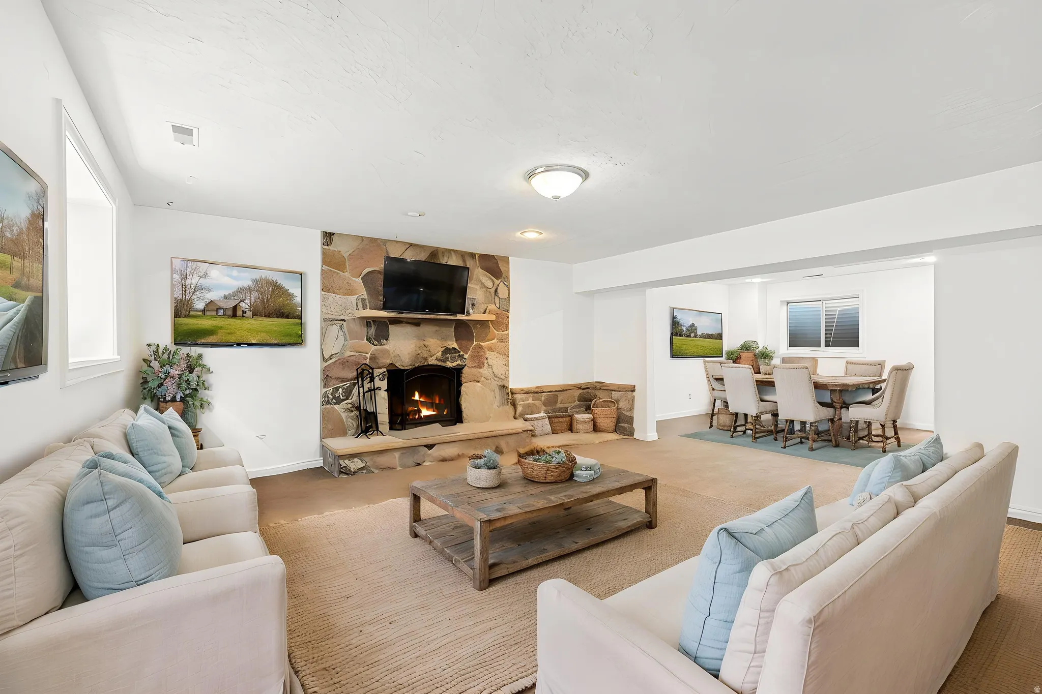 Virtually staged - Spacious living area featuring a prominent stone fireplace with a hearth, white walls, and a recessed dining area with a window
