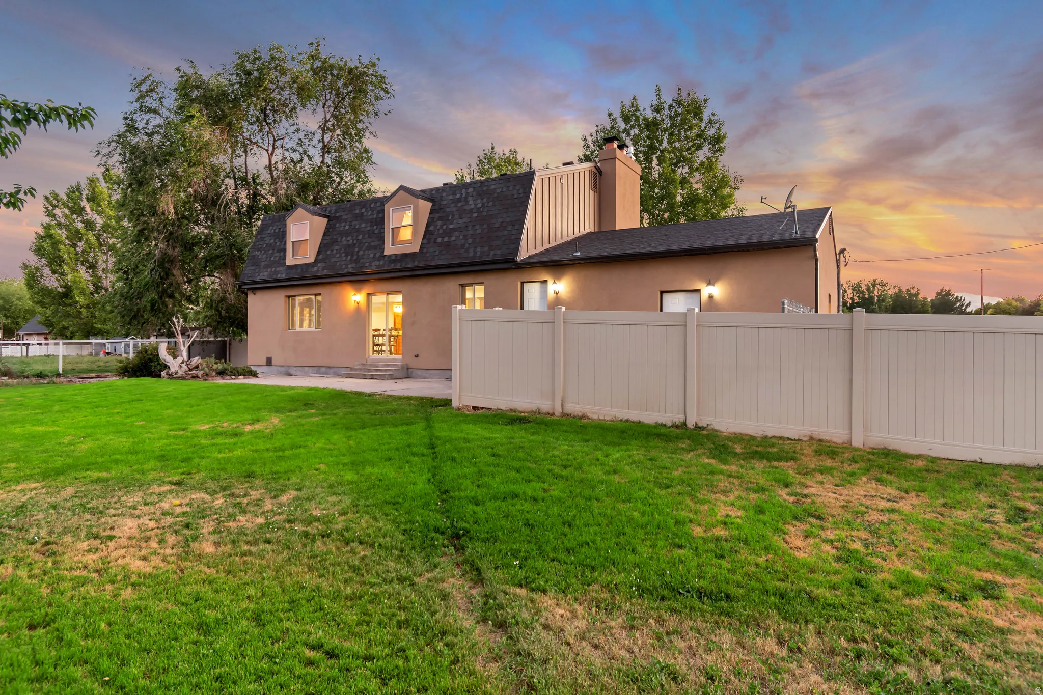 Expansive backyard with a manicured lawn, a concrete patio, and a light-toned privacy fence