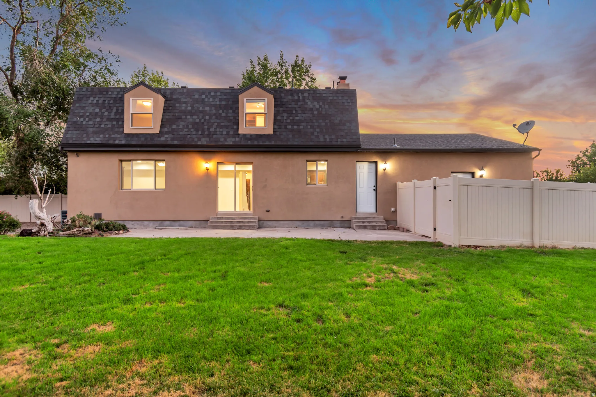 Rear exterior with a stucco finish and a dark shingle roofline
