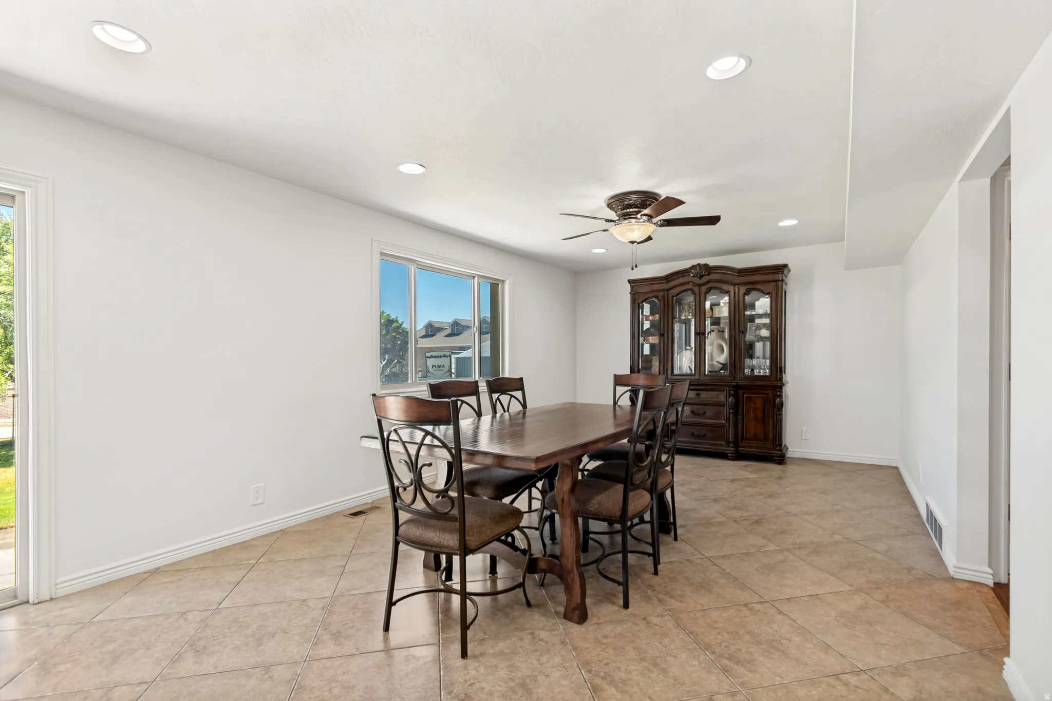 Spacious dining area featuring neutral tile flooring, recessed lighting, and a ceiling fan