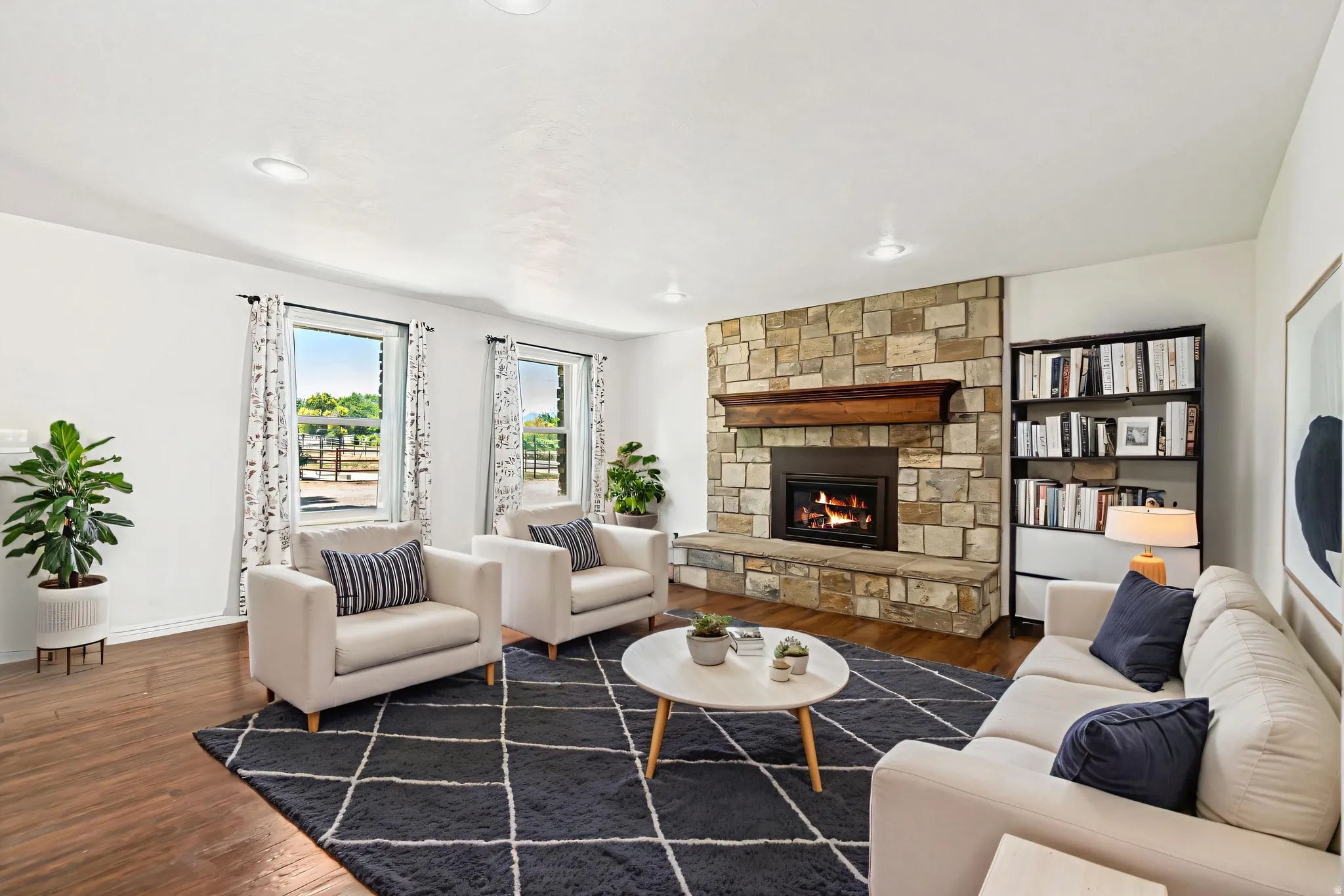 Virtually Staged - Living area featuring a stone fireplace with a wood mantle, wood-finish flooring, recessed lighting, and built-in shelving