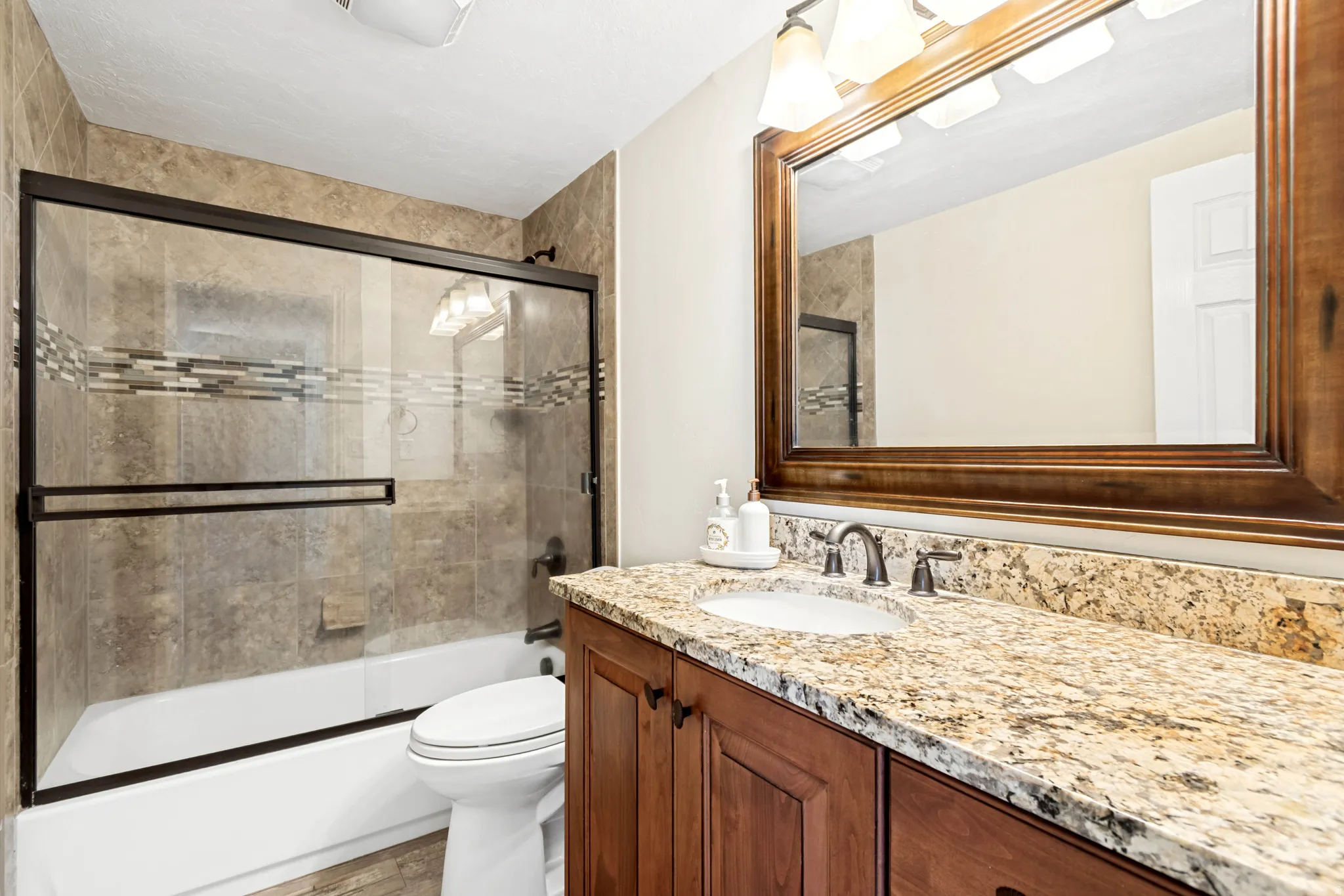 Bathroom featuring a spacious single vanity with a stone countertop, an integrated sink, and a dark wood-finish cabinet