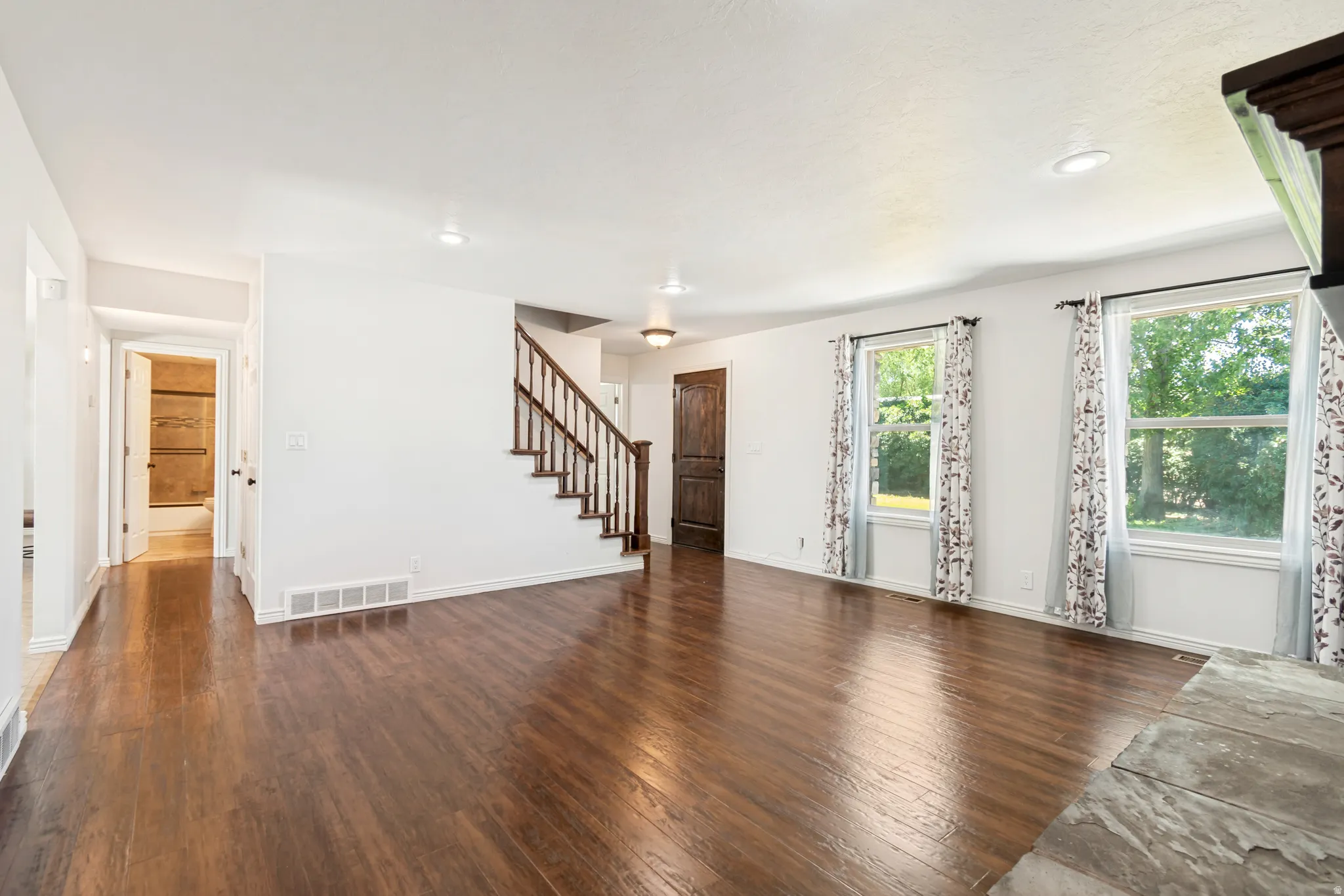 Spacious living area featuring rich wood-finish flooring, white walls, and recessed lighting