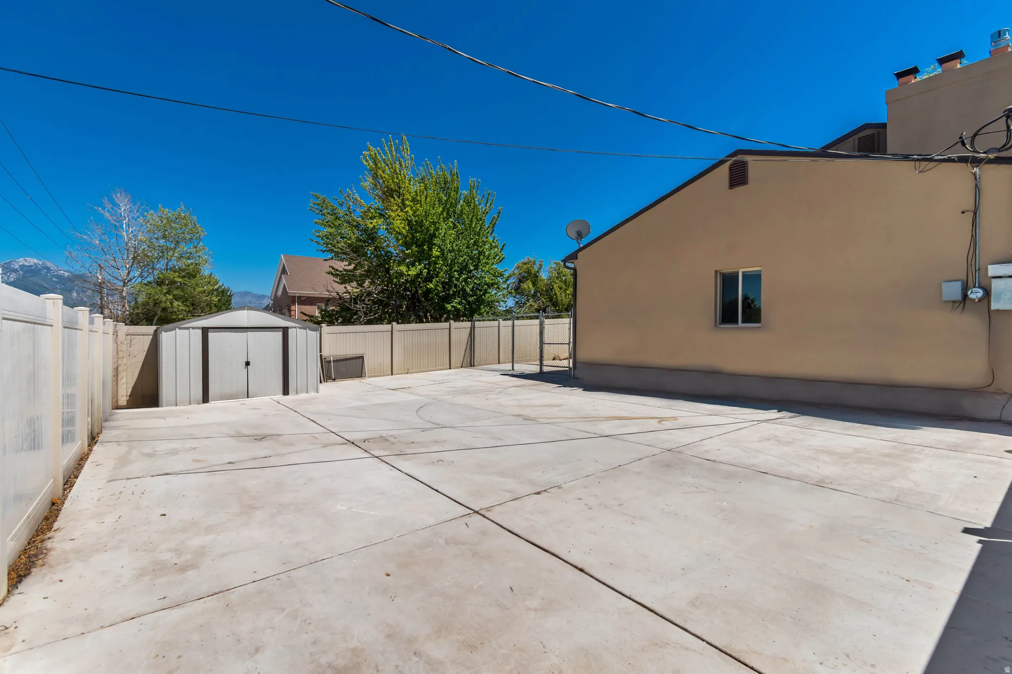 Expansive concrete patio area, fully fenced with a combination of vinyl and wood fencing