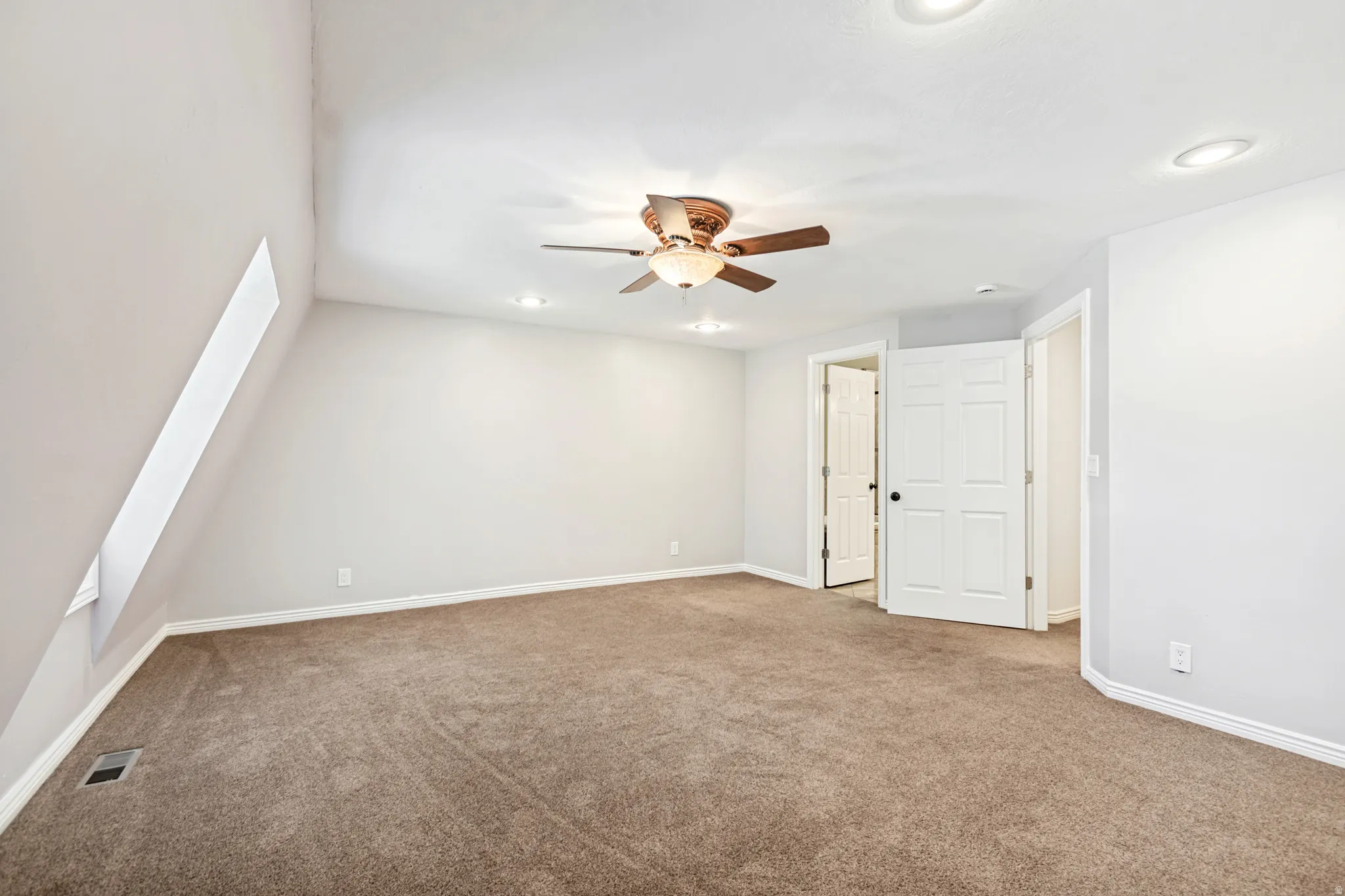 Spacious master bedroom featuring vaulted ceilings, recessed lighting, and a ceiling fan with integrated light fixture