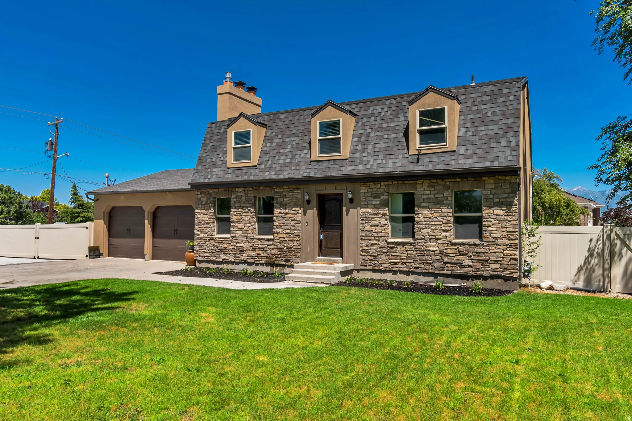 Stone facade home with a shingle roof and multiple dormer windows