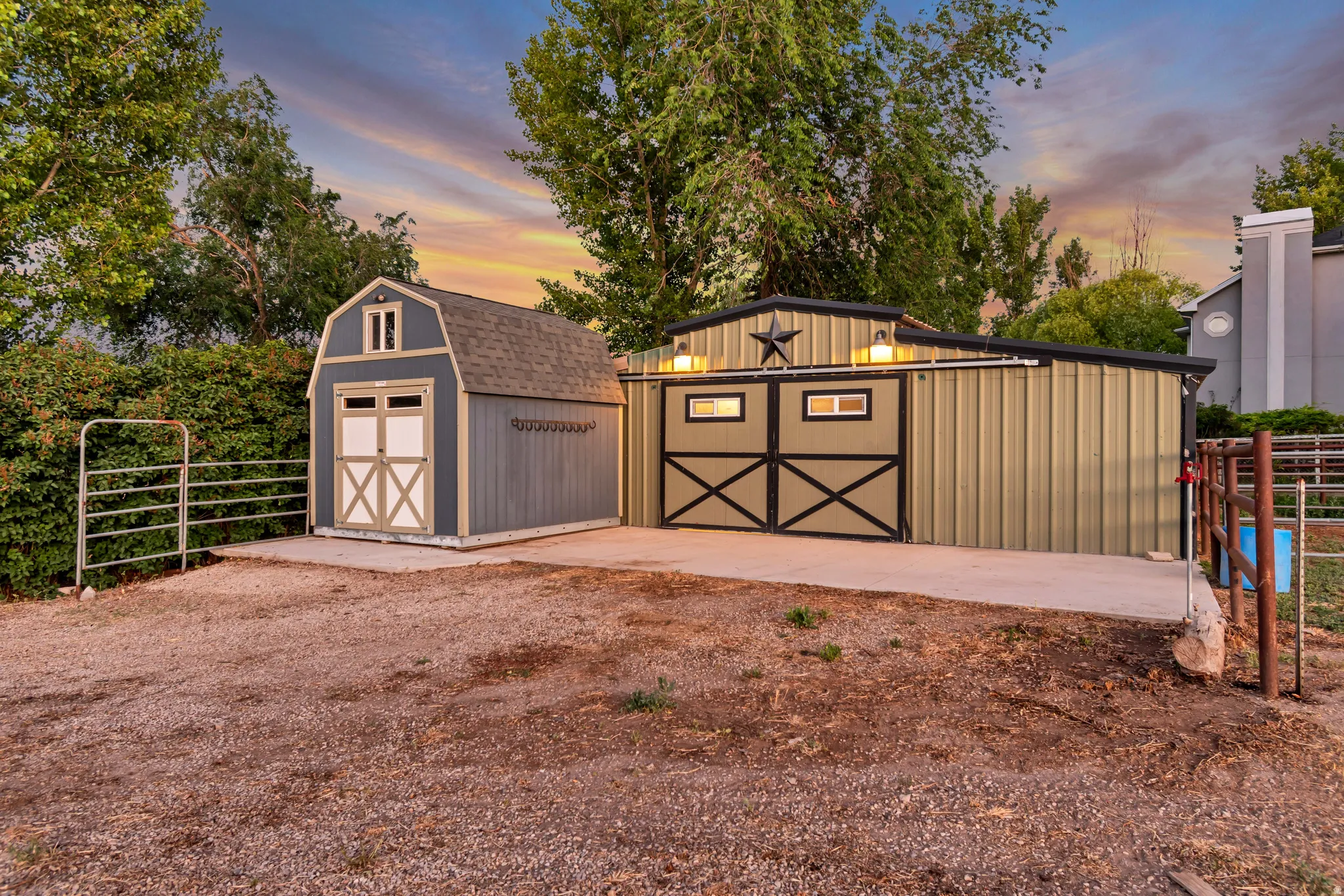 Two detached structures, one featuring a gambrel roof and double doors, the other a metal-sided building with exterior lighting and a decorative star