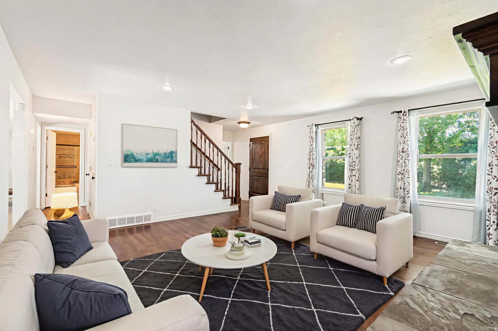 Virtually staged - Spacious living area featuring wood-finish flooring, white walls, and recessed lighting