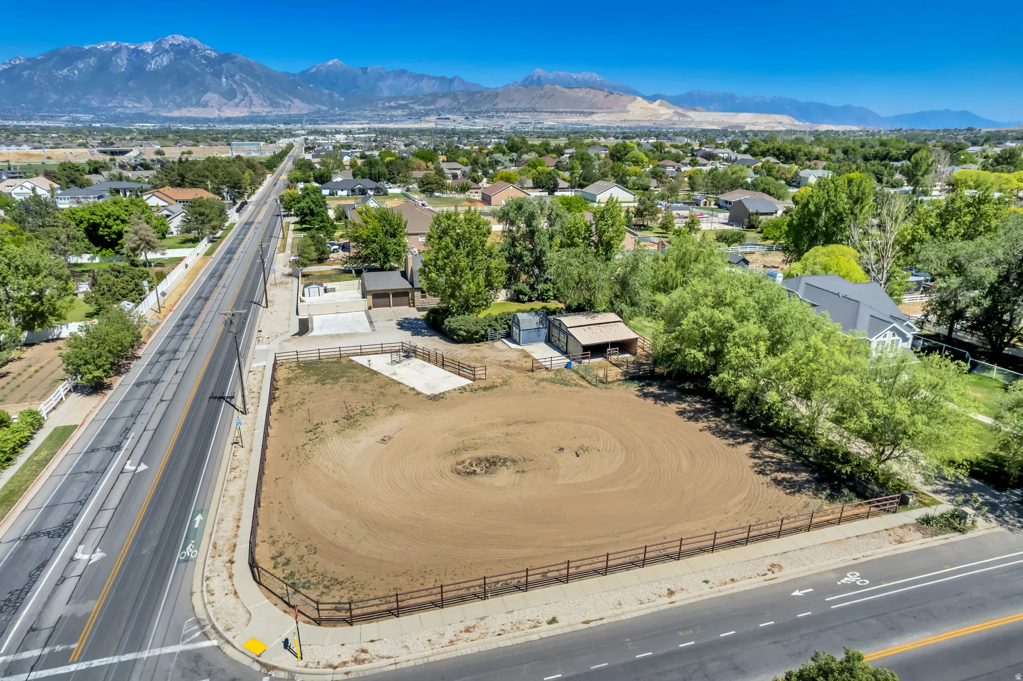 Expansive corner lot featuring a fenced riding arena, a detached auxiliary building, and a paved concrete pad