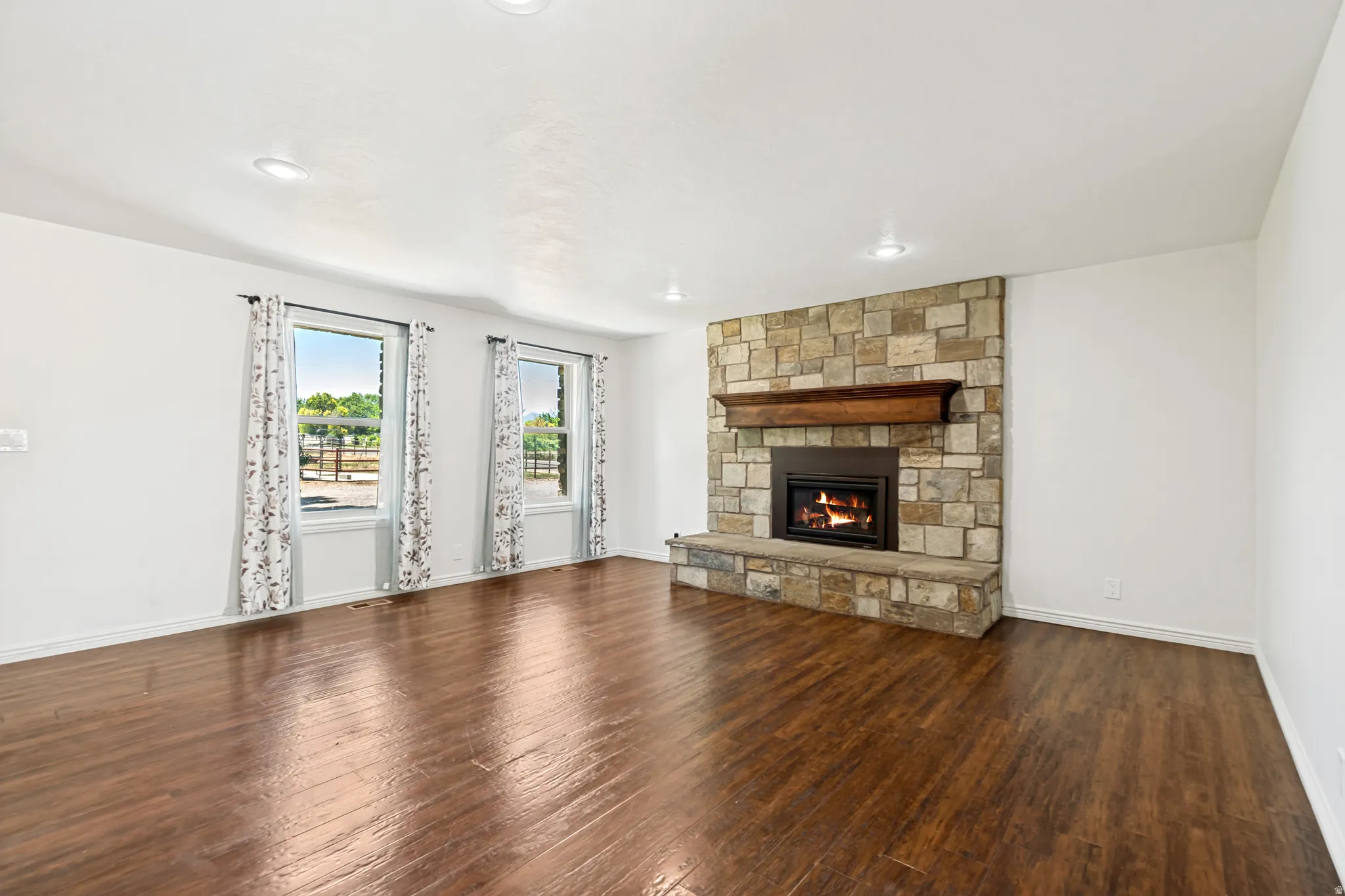 Spacious interior featuring wood-finish flooring and a stone-faced fireplace with a substantial hearth and wood mantel