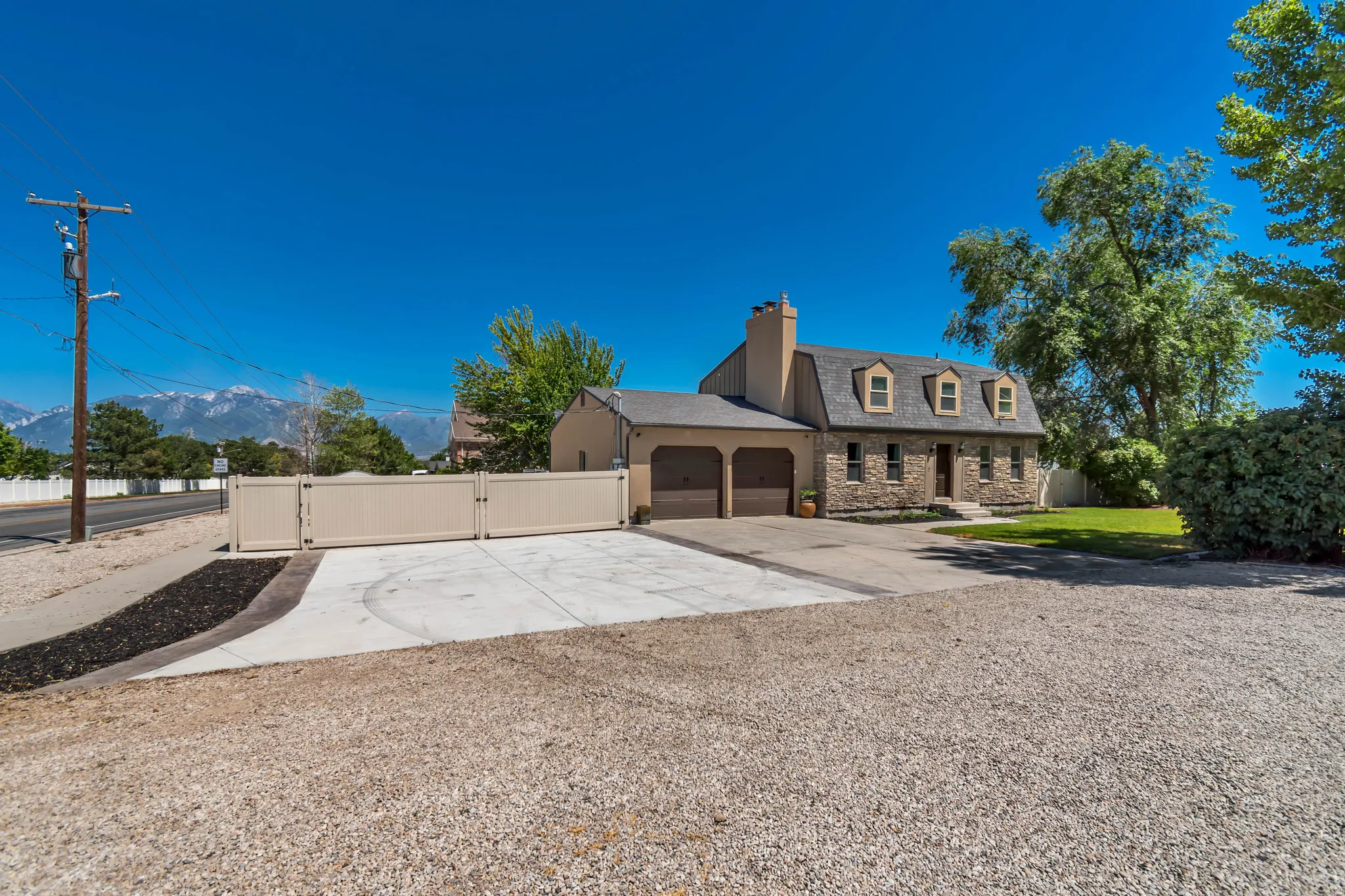 Two-story home with a stone and stucco exterior, featuring a three-car garage and a paved driveway