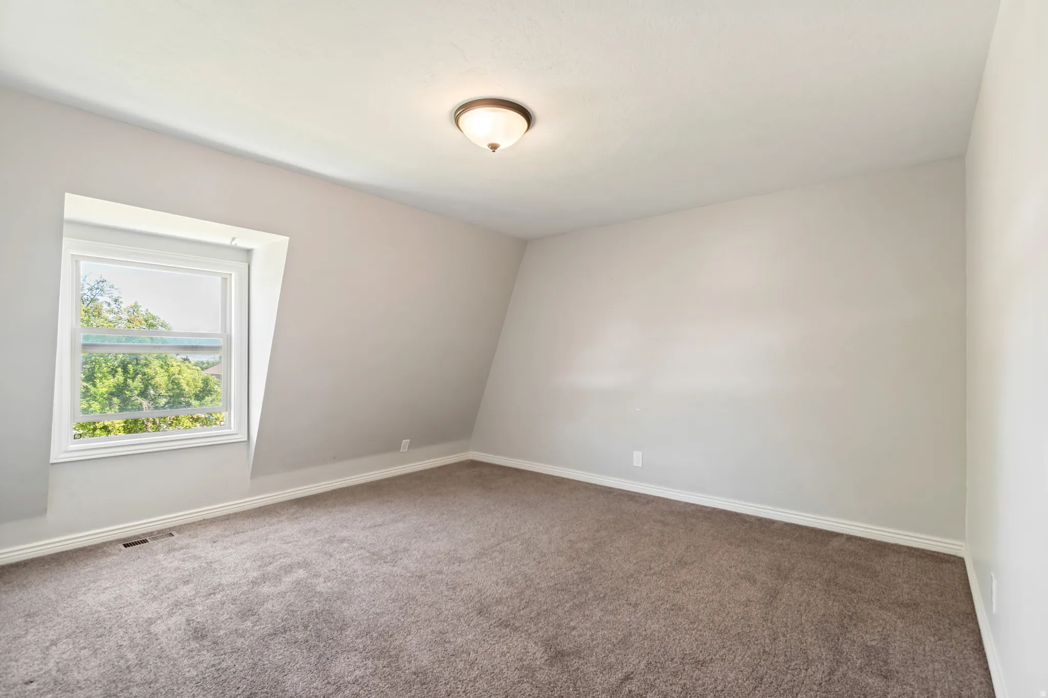 Spacious room featuring sloped ceilings and light gray walls