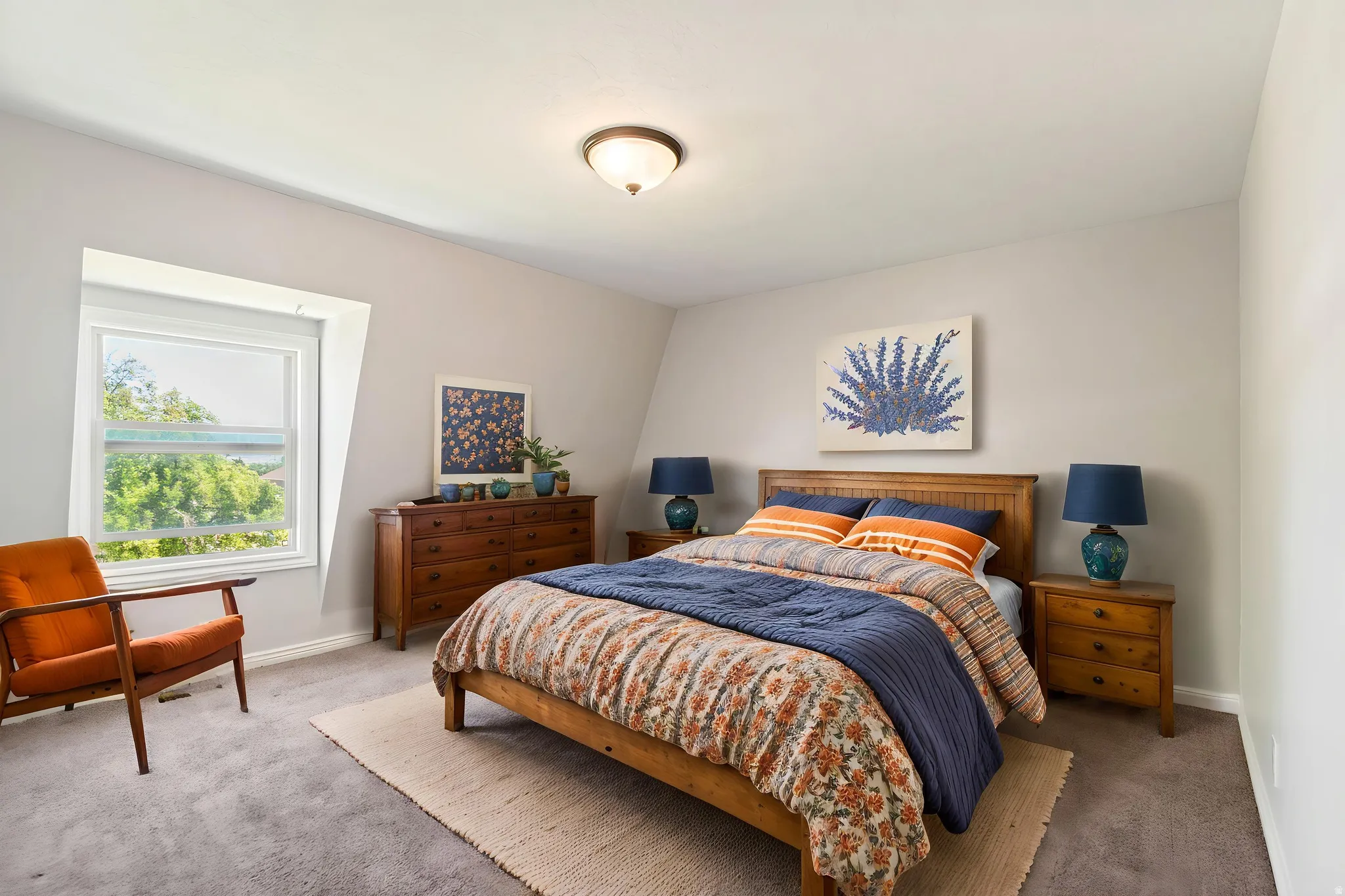 Virtually staged - Bedroom featuring a window with exterior tree scenery, gray wall paint, gray carpet flooring, wood-finish flooring trim, and a ceiling-mounted light fixture