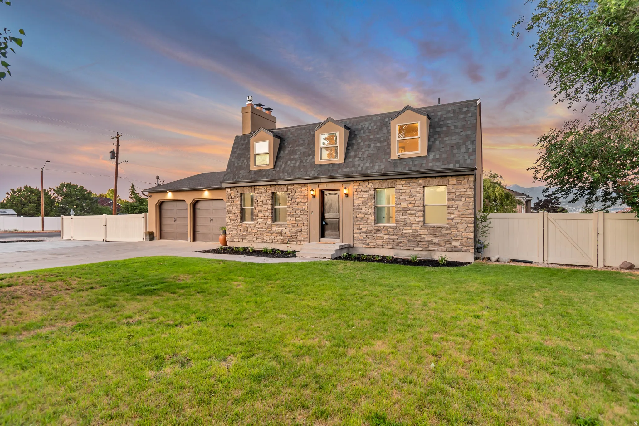 Stately stone and stucco exterior with a dark shingled roof