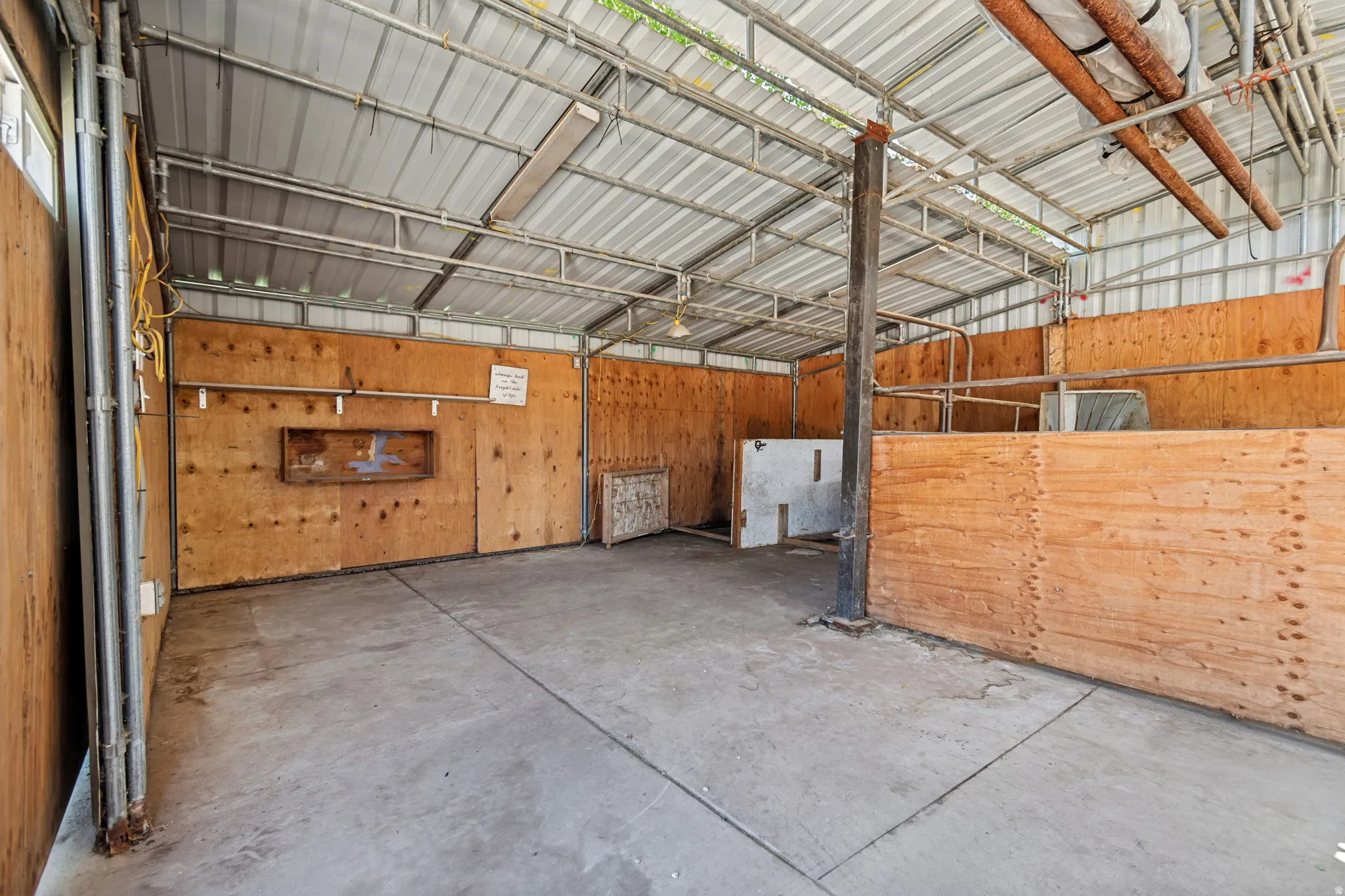 Open-air structure featuring a concrete floor and plywood paneling