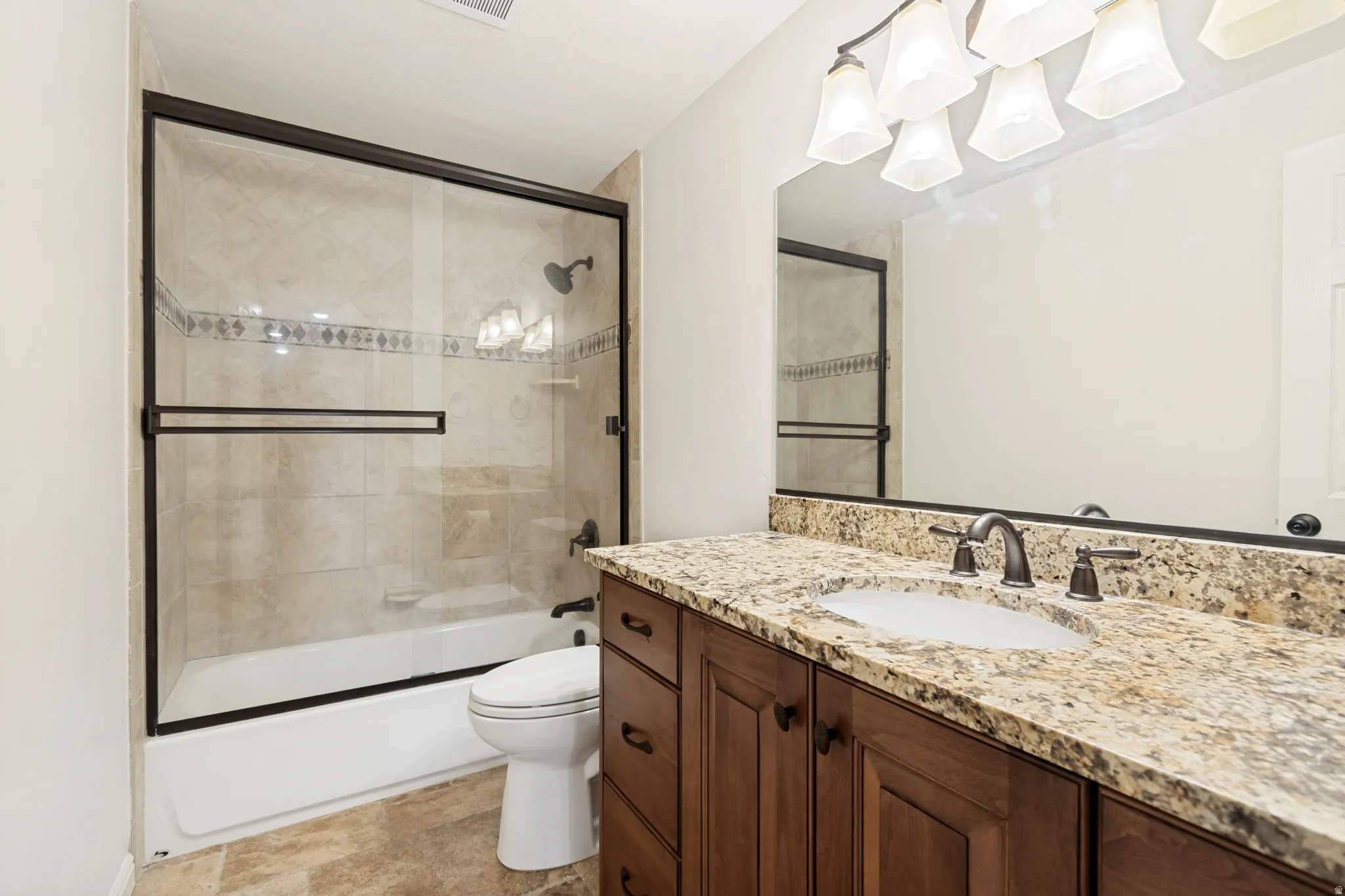 Bathroom featuring an integrated vanity with a stone countertop, a bronze-finish faucet, and a large mirror