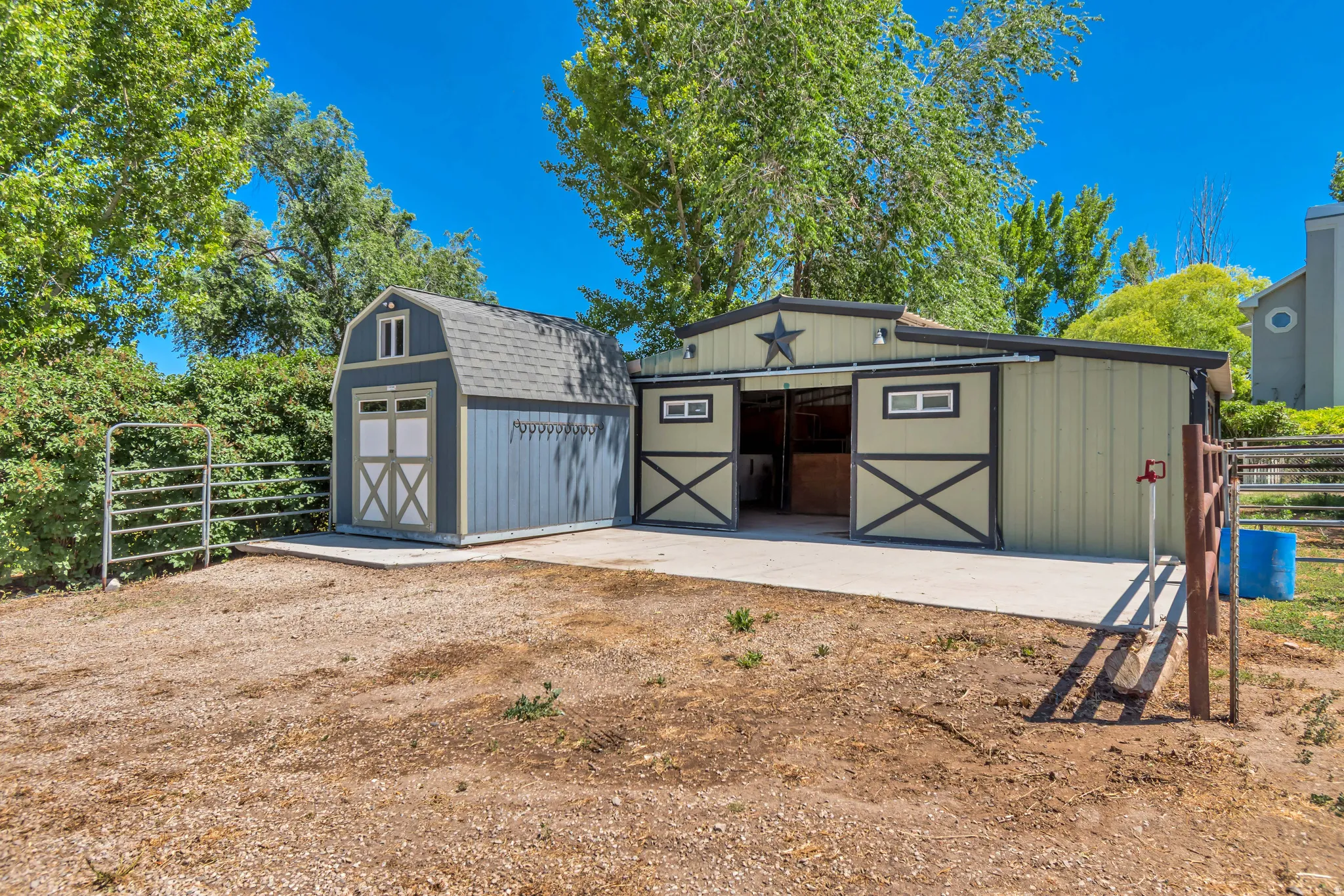 Equestrian facility featuring a multi-stall barn with sliding doors, an attached storage shed, and concrete aprons