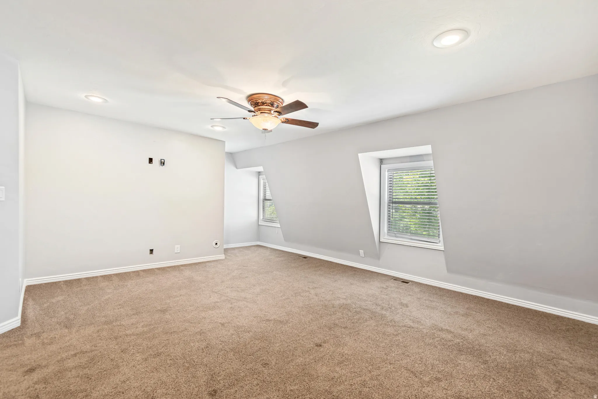 Spacious room featuring sloped ceilings, recessed lighting, and a ceiling fan with light fixture