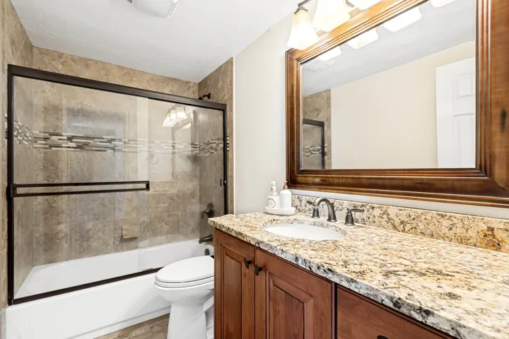Bathroom featuring a spacious single vanity with a stone countertop, an integrated sink, and a dark wood-finish cabinet