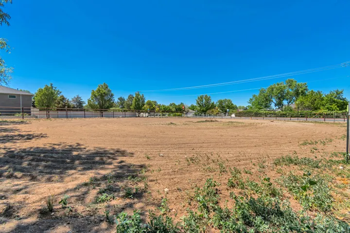 Expansive cleared lot featuring a perimeter fence and mature trees along the boundary