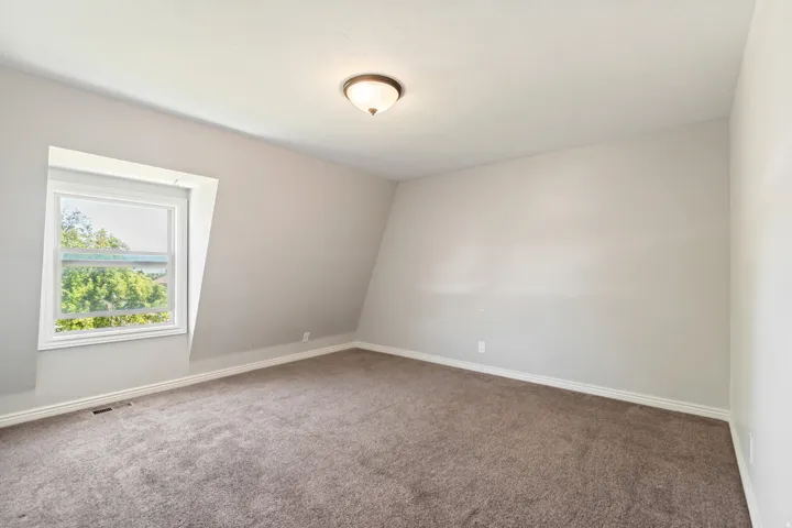 Spacious room featuring sloped ceilings and light gray walls