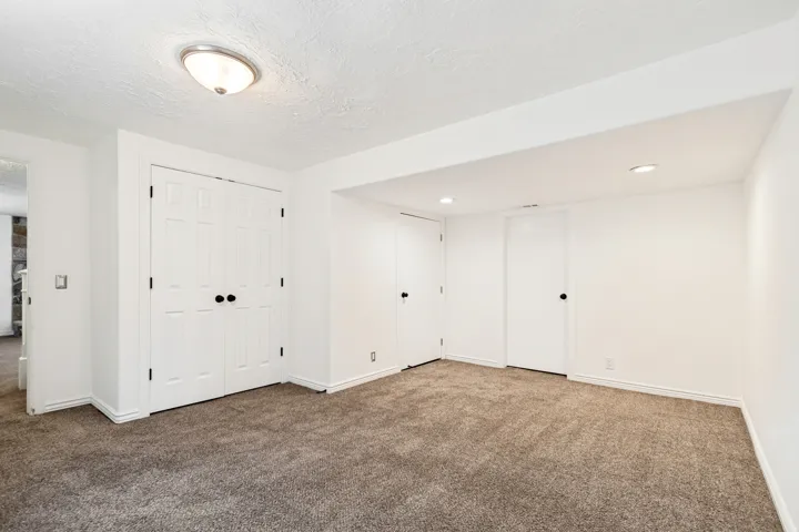 Spacious room featuring new carpeting, crisp white walls, multiple recessed lights, and a flush mount ceiling fixture