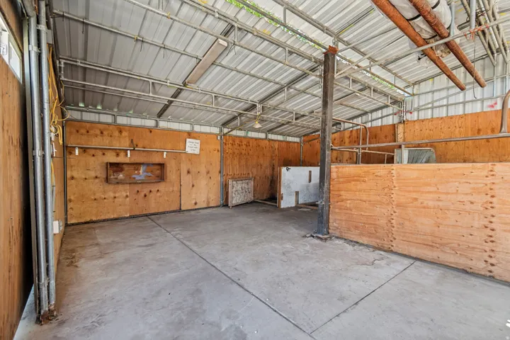 Open-air structure featuring a concrete floor and plywood paneling