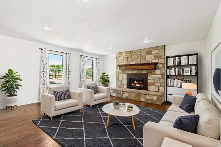 Virtually Staged - Living area featuring a stone fireplace with a wood mantle, wood-finish flooring, recessed lighting, and built-in shelving