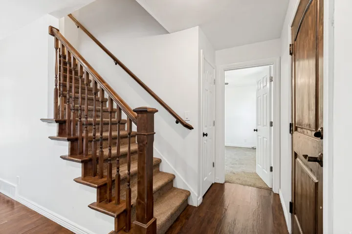 Staircase featuring wood balusters and a carpeted tread, set against white walls