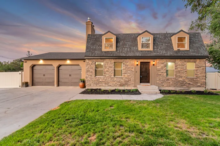 Two-story residence featuring a stone and stucco exterior, a dark shingle roof, and three dormer windows