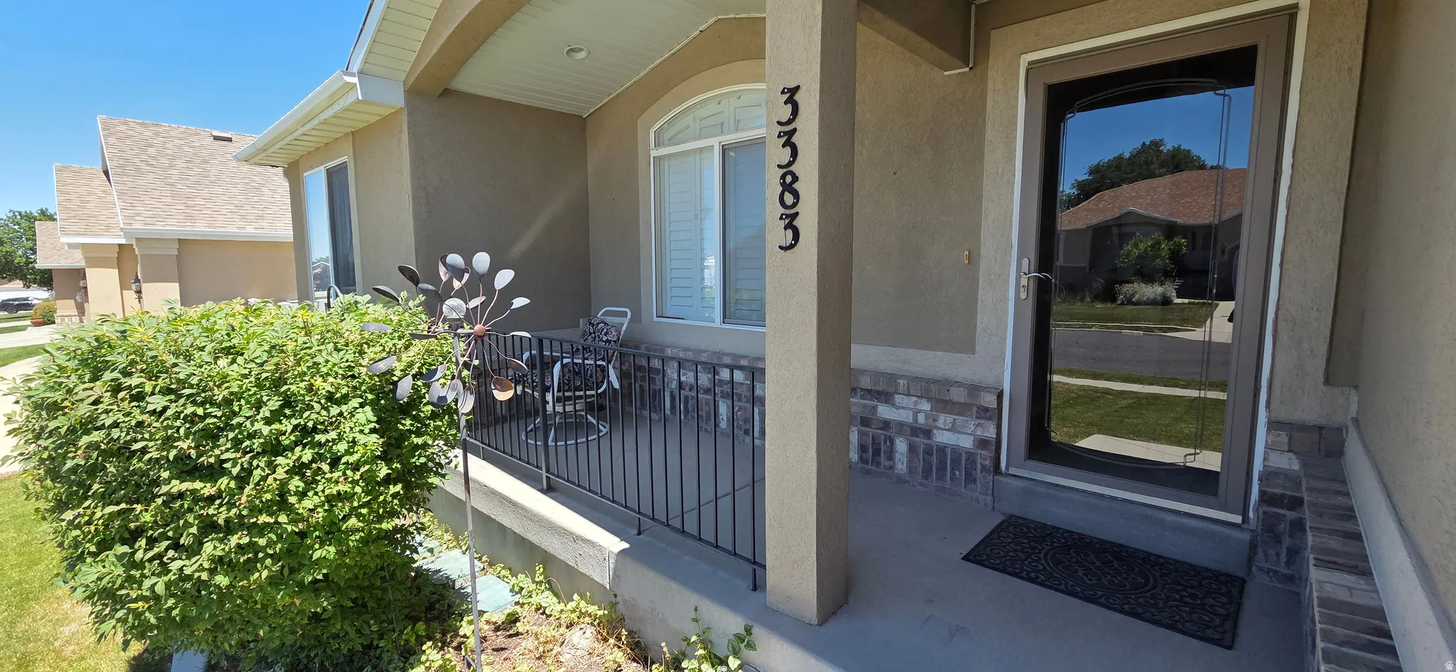 Covered front porch featuring a decorative railing, stucco exterior, and brick-look accent siding