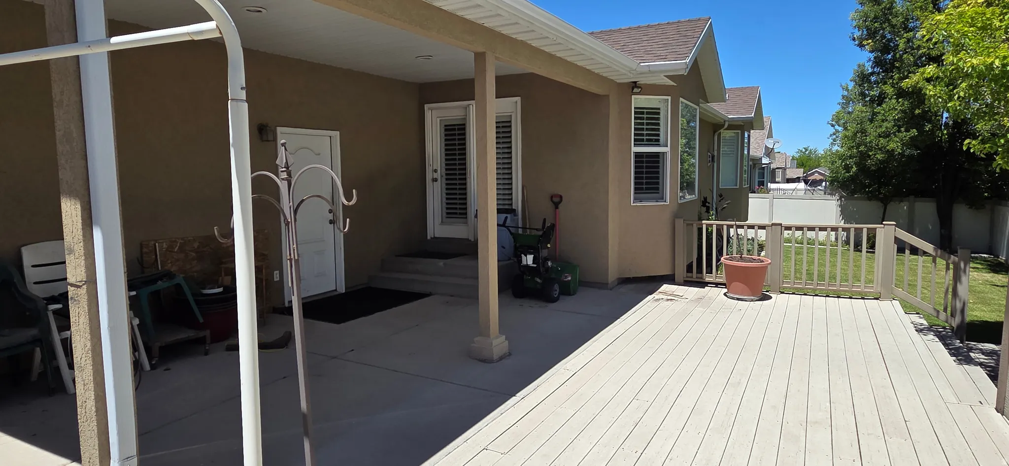 Outdoor living area featuring a covered patio, a deck, stucco siding, a shingle roof, and a fenced yard