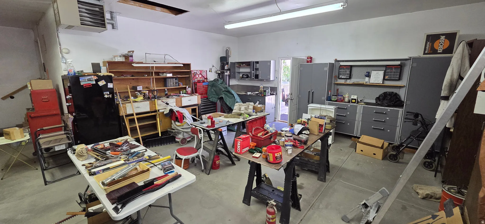 Spacious heated garage with overhead fluorescent lighting and workshop