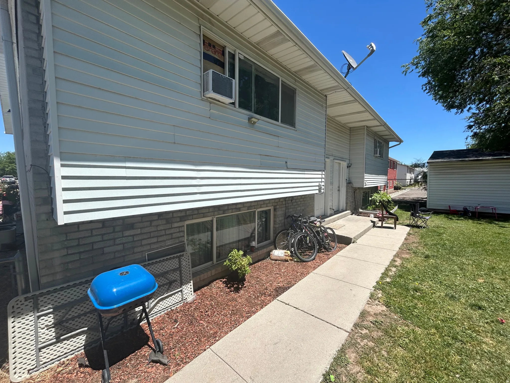 Exterior featuring light-toned horizontal siding above a brick-finish foundation