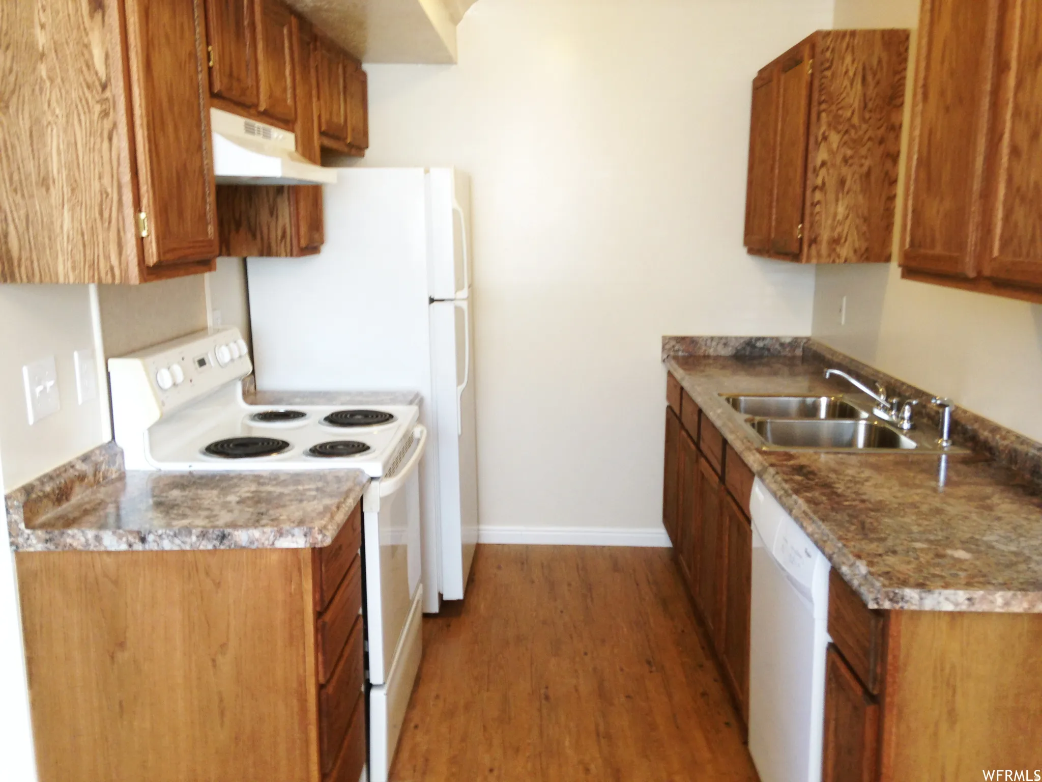 Galley kitchen featuring wood-finish flooring, wood cabinetry, and patterned laminate countertops